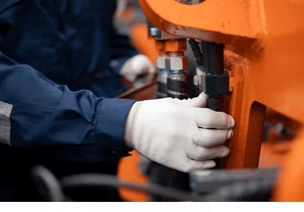 Technician fitting hydraulic lines on a HERESTRONG excavator