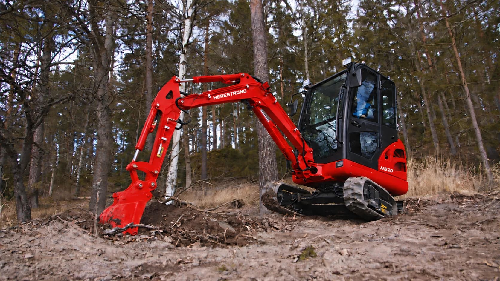 HERESTRONG HS20 compact excavator digging on a forest jobsite